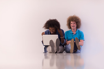 Image showing multiethnic couple sitting on the floor with a laptop and tablet