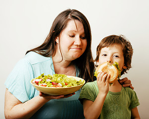 Image showing mature woman holding salad and little cute boy with hamburger te