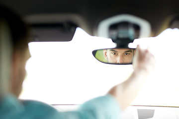 Image showing man driving car adjusting rearview mirror