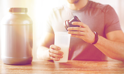 Image showing close up of man with protein shake bottle and jar