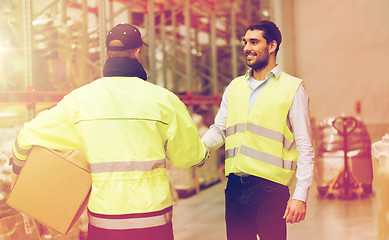 Image showing men in safety vests shaking hands at warehouse