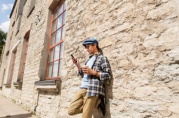 Image showing man with smartphone drinking coffee on city street