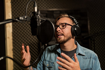 Image showing man with headphones singing at recording studio