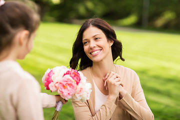 Image showing girl giving with flowers to mother in summer park