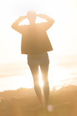 Image showing Woman on sandy beach watching sunset.