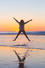 Image showing Young beautiful woman jumping in the beach.