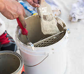 Image showing Professional Painter Loading Paint Onto Brush From Bucket