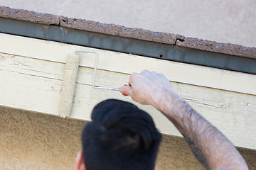 Image showing Professional Painter Using Small Roller to Paint House Fascia