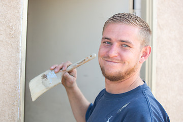 Image showing Young Caucasian Man Smiling As He Is Painting House