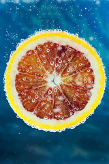 Image showing Blood orange slice falling into water