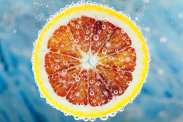 Image showing Blood orange slice falling into water