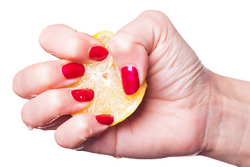 Image showing Hand with manicured nails squeeze lemon on white