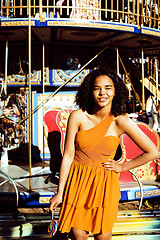 Image showing cool real teenage girl with candy near carousels at amusement pa