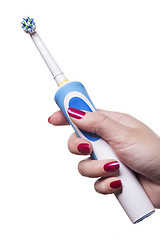 Image showing Hand holds electric toothbrush against white