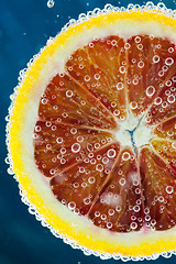 Image showing Blood orange slice falling into water