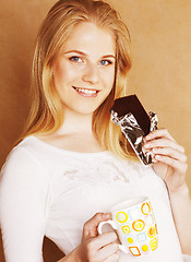 Image showing young cute blond girl eating chocolate and drinking coffee close