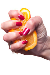 Image showing Hand with manicured nails touch an orange on white