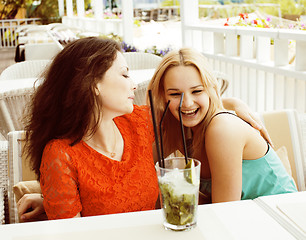 Image showing portrait of two pretty modern girl friends in cafe open air inte