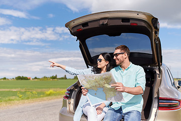 Image showing happy man and woman with road map at hatchback car