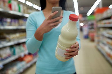 Image showing woman with smartphone buying milk at supermarket