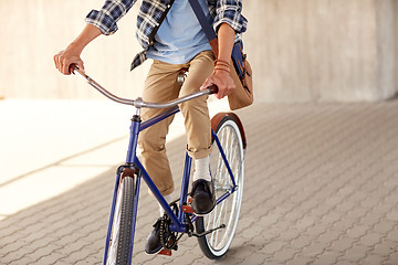 Image showing young hipster man with bag riding fixed gear bike