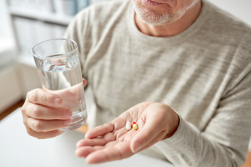 Image showing close up of old man hands with pills and water