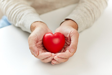 Image showing close up of senior man with red heart in hands