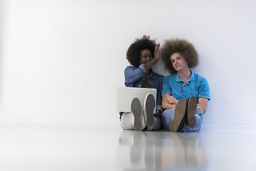 Image showing multiethnic couple sitting on the floor with a laptop and tablet