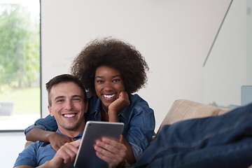 Image showing multiethnic couple relaxing at  home with tablet computers