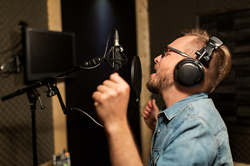 Image showing man with headphones singing at recording studio