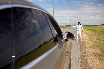 Image showing woman hitchhiking and stopping car with thumbs up