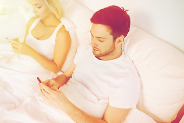 Image showing couple with smartphones in bed