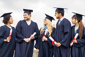 Image showing happy students in mortar boards with diplomas