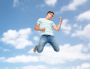 Image showing happy man jumping and playing imaginary guitar