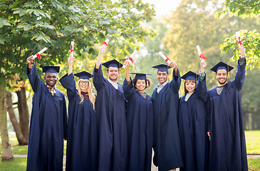 Image showing happy students in mortar boards with diplomas