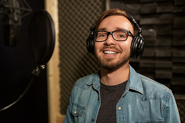 Image showing man with headphones singing at recording studio