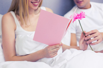 Image showing close up of couple in bed with postcard and flower