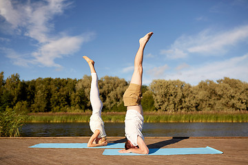 Image showing couple making yoga headstand on mat outdoors