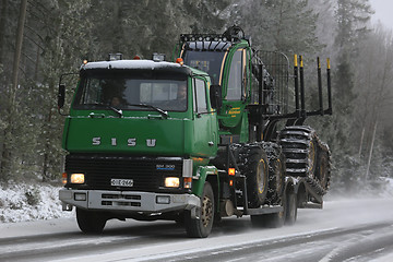 Image showing Green SISU Truck Hauls John Deere Forwarder in Winter