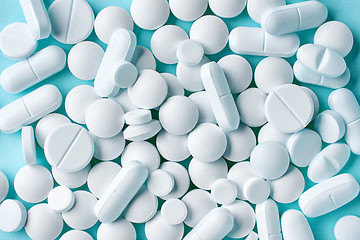 Image showing various white pills on blue background