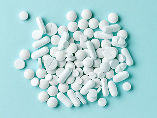 Image showing various white pills on blue background