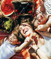 Image showing cute happy family on picnic laying on green grass mother and kids, warm summer vacations close up, brother and sister 