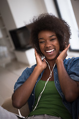 Image showing African american woman at home in chair with tablet and head pho