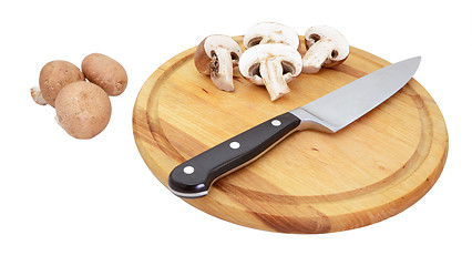 Image showing Chestnut mushrooms with sliced halves on wooden board with knife