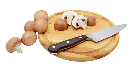 Image showing Whole and halved chestnut mushrooms with knife on wooden board