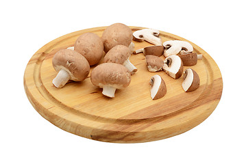 Image showing Whole and sliced chestnut mushrooms on a wooden cutting board