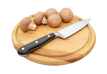 Image showing Fresh chestnut mushrooms with sharp knife on a wooden board