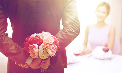 Image showing close up of man hiding flowers behind from woman