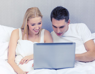 Image showing smiling couple in bed with laptop computer