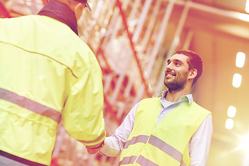 Image showing men in safety vests shaking hands at warehouse